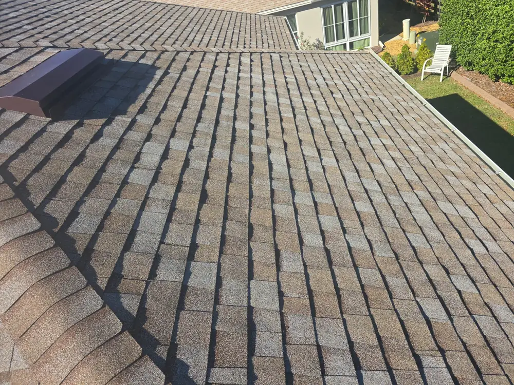 Three Logams Roofing team members beside a company yard sign at a Central Florida home being re-roofed