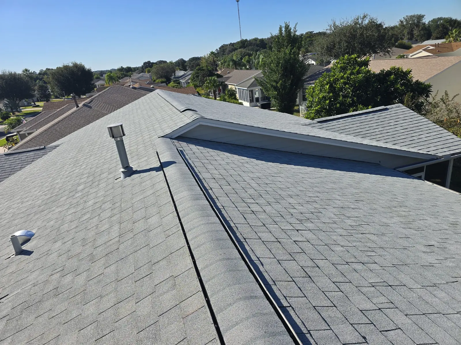 Three Logams Roofing team members beside a company yard sign at a Central Florida home being re-roofed